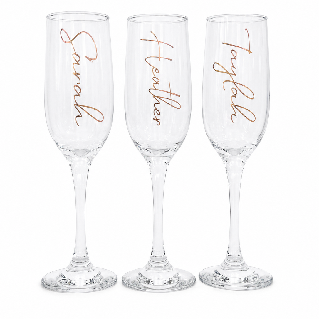 Three champagne flutes with personalized names in rose gold on a white background