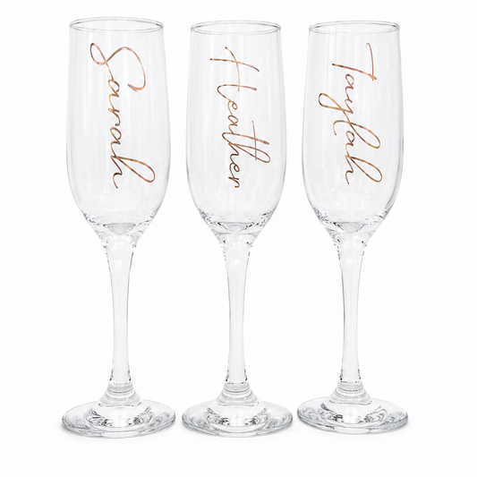 Three champagne flutes with personalized names in rose gold on a white background