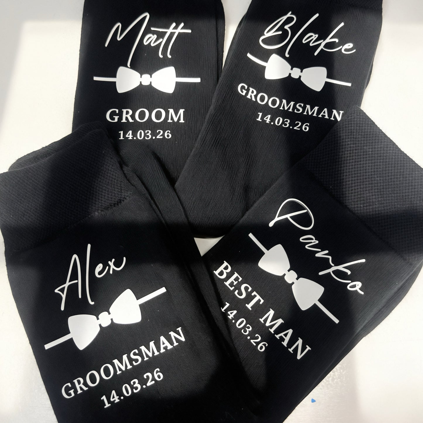 Black socks with white text for groomsmen on a white background