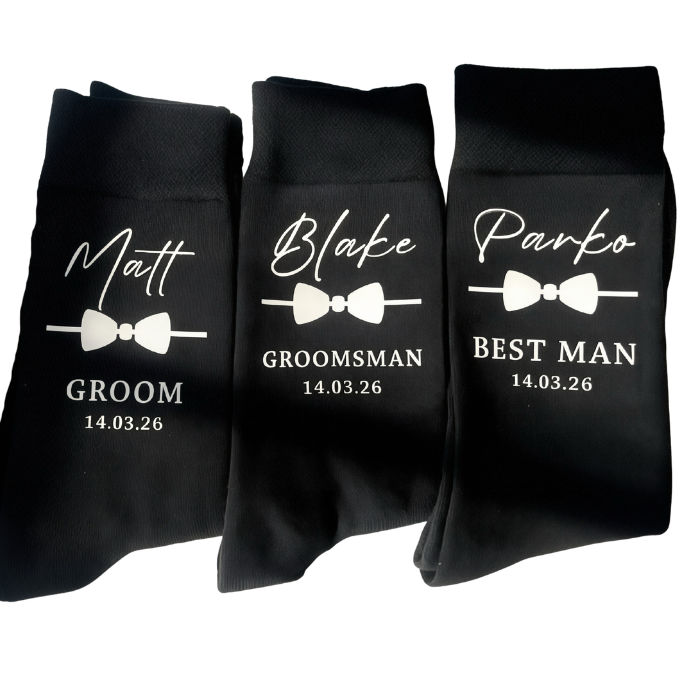 Three black socks with white text for groom, groomsman, and best man on a white background