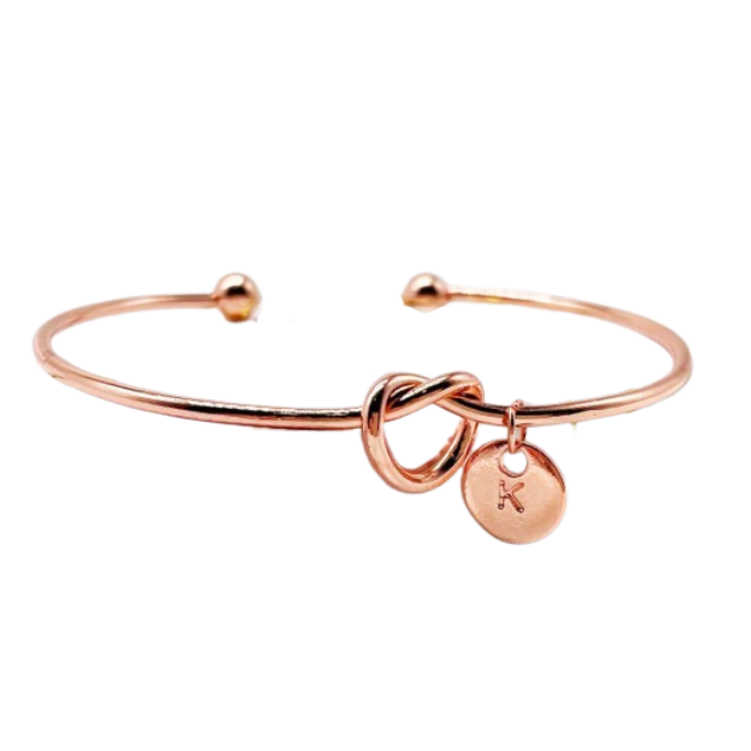 Rose gold bracelet with a knot design and round tag on a white background