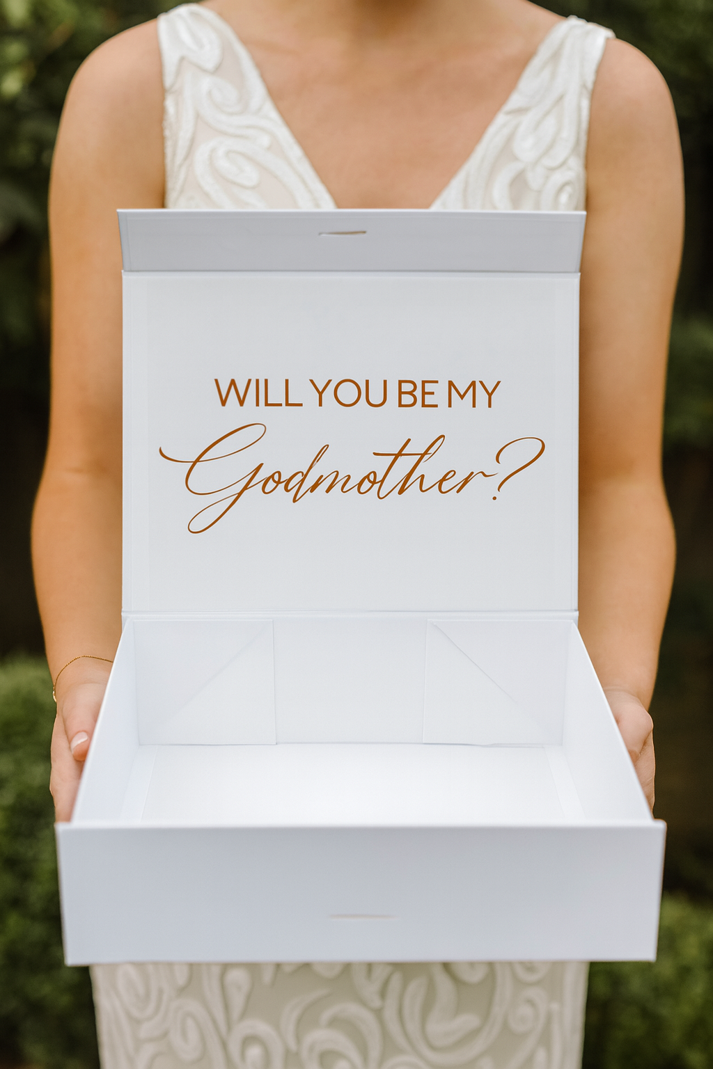 Person holding a box with 'Will You Be My Godmother?' text.