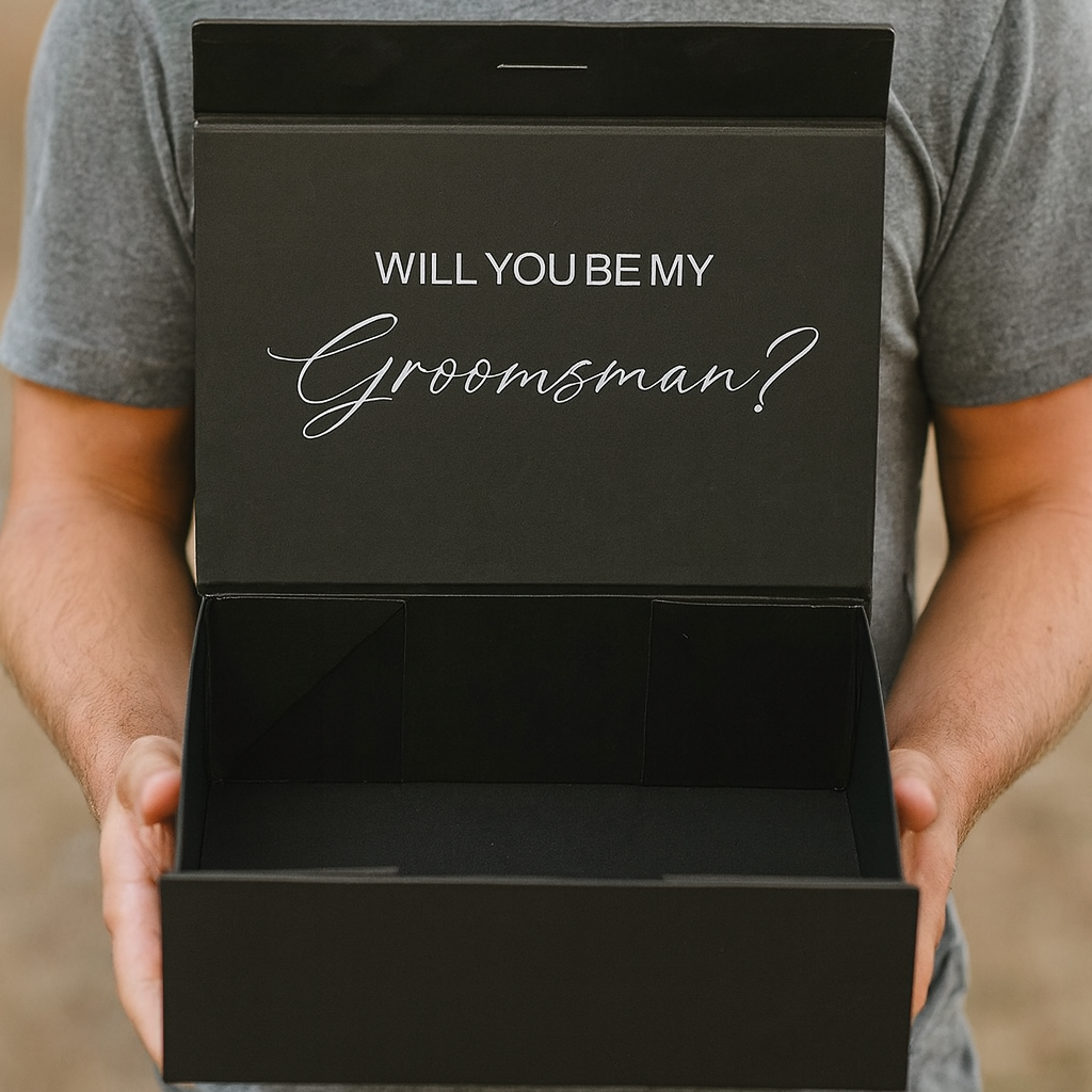 Man holding a black box with 'Will You Be My Groomsman?' text.