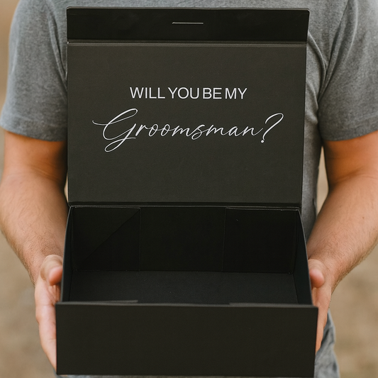 Man holding a black box with 'Will You Be My Groomsman?' text.